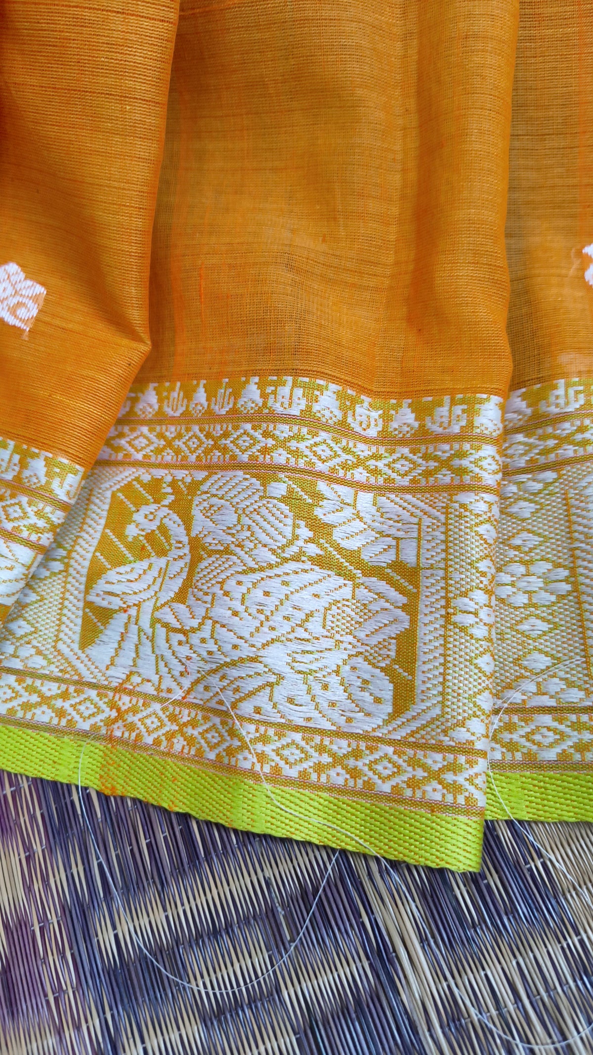 Orange cotton baluchari saree, with woven motifs in the border & pallu in white and neon green. Bengal handloom ideal for festivals & everyday celebrations.