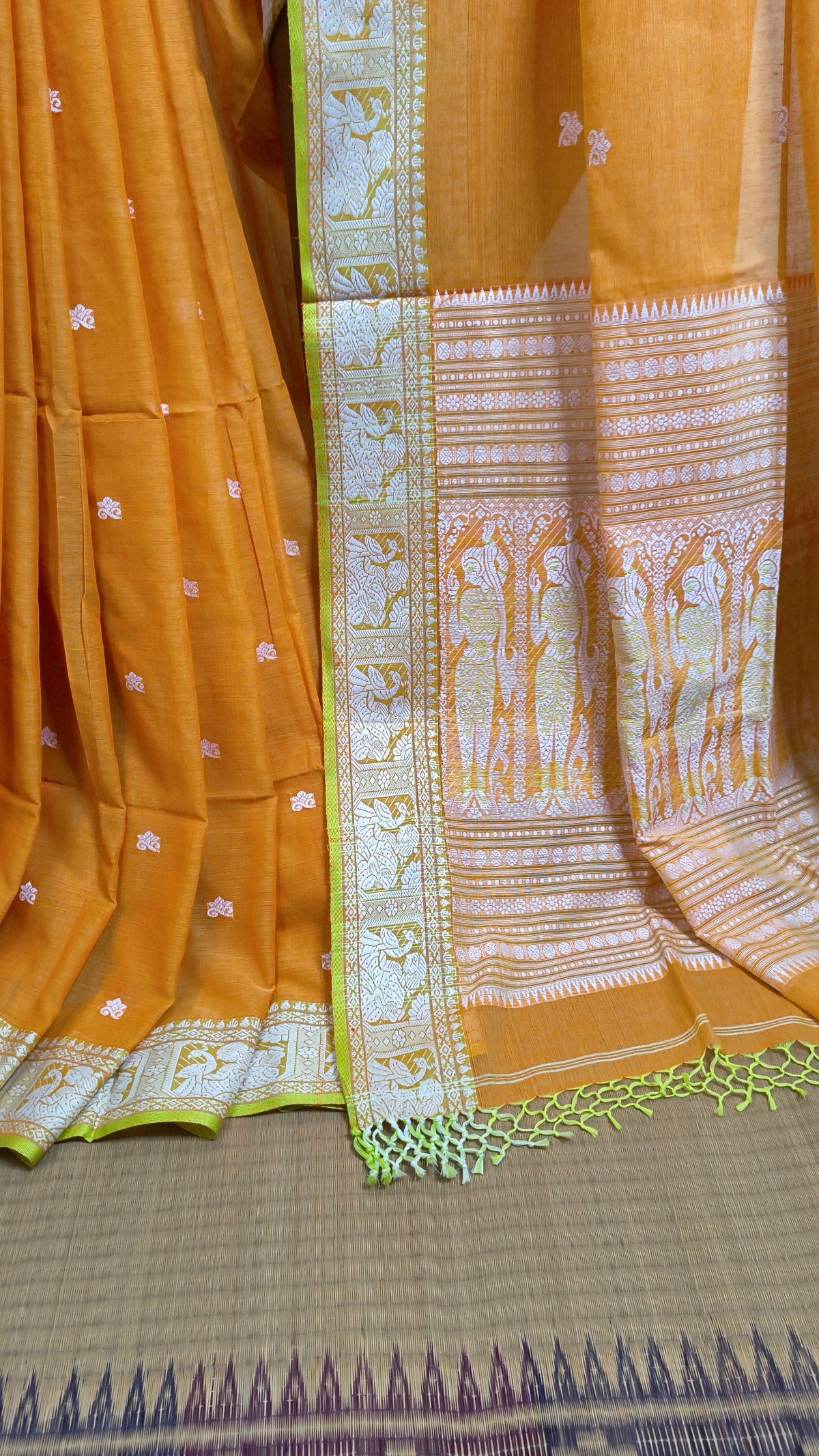 Orange cotton baluchari saree, with woven motifs in the border & pallu in white and neon green. Bengal handloom ideal for festivals & everyday celebrations.